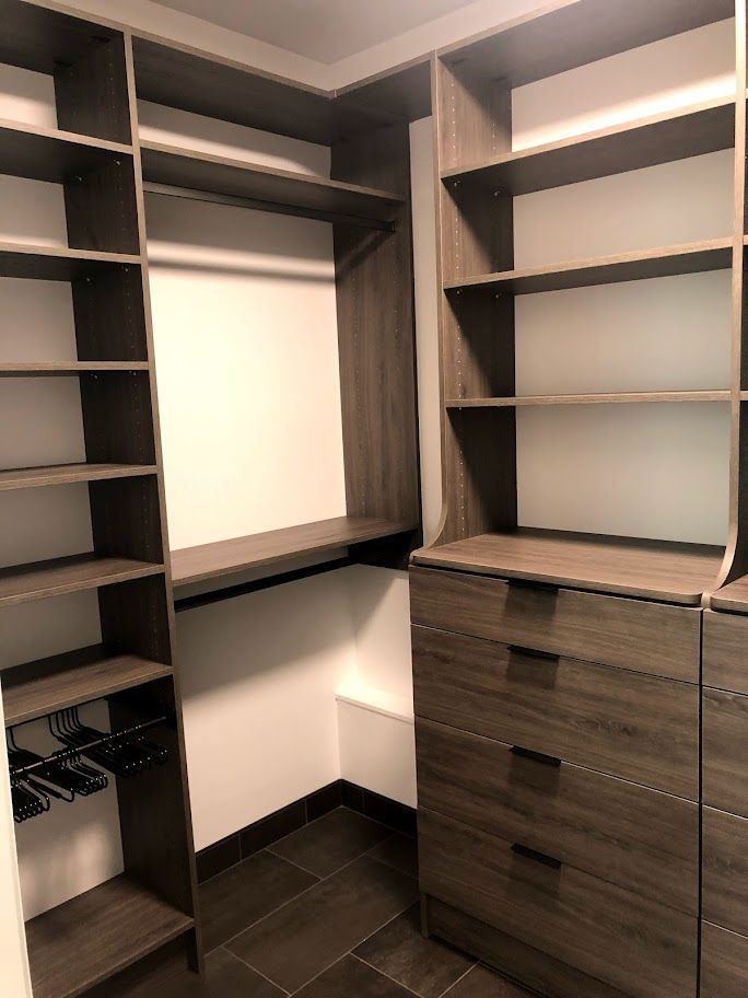 a walk in closet with lots of shelves and drawers .