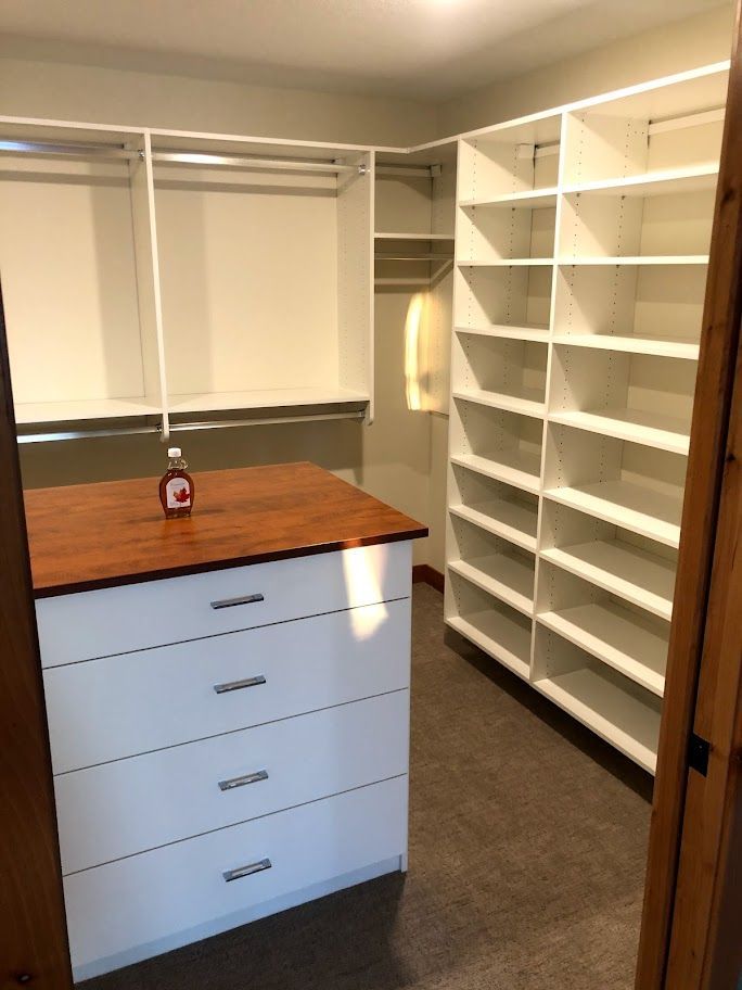 a walk in closet with lots of shelves and drawers
