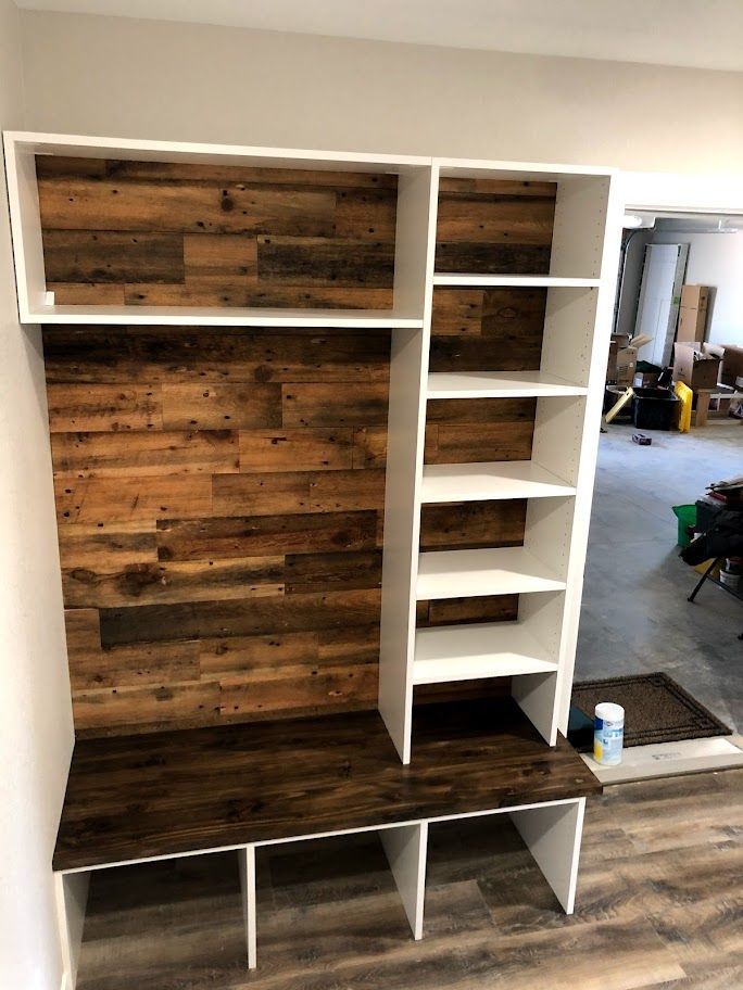 a room with a wooden wall and shelves and a bench .