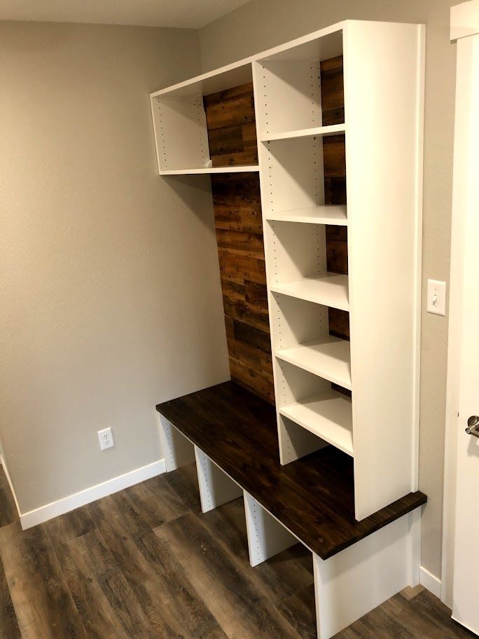 a room with a bench and shelves in it .