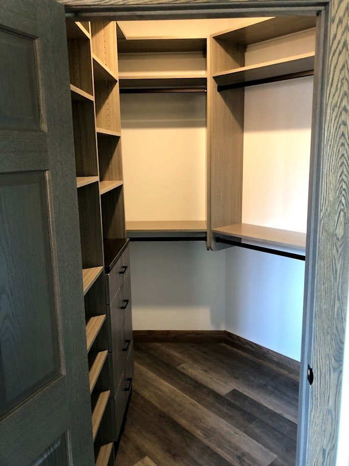 a walk in closet with lots of shelves and drawers .