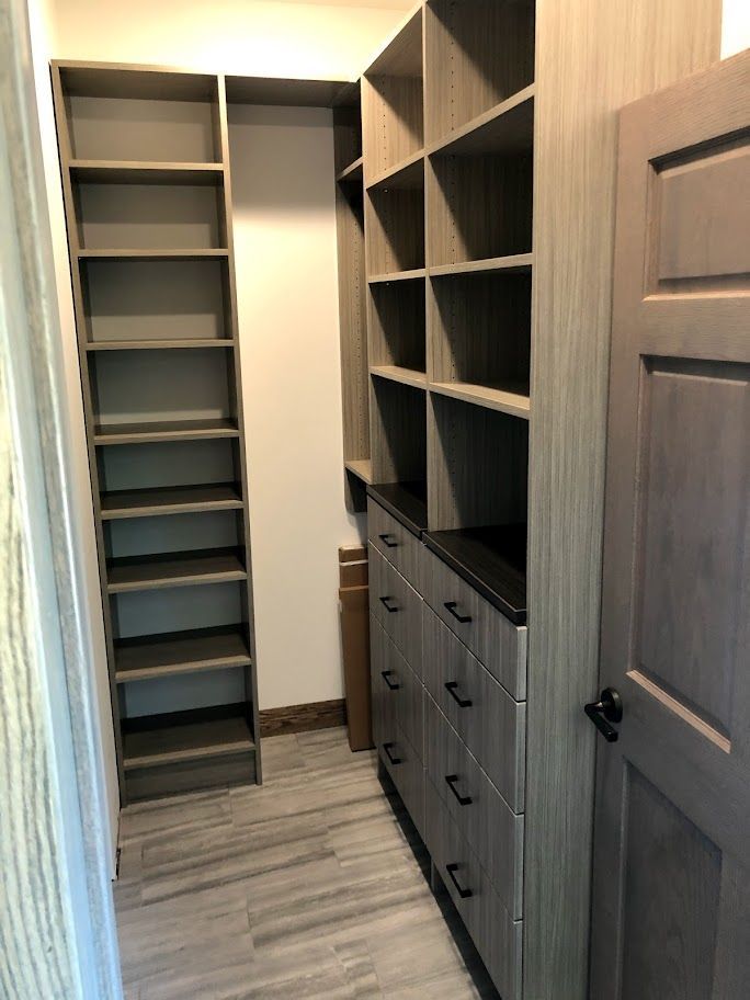 a walk in closet with lots of shelves and drawers .