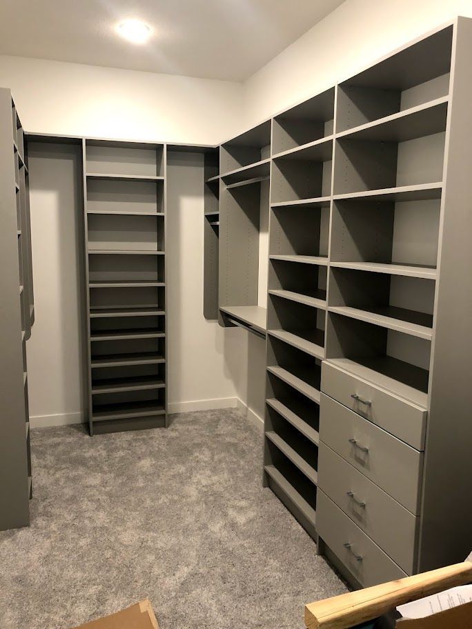 a walk in closet with lots of shelves and drawers .