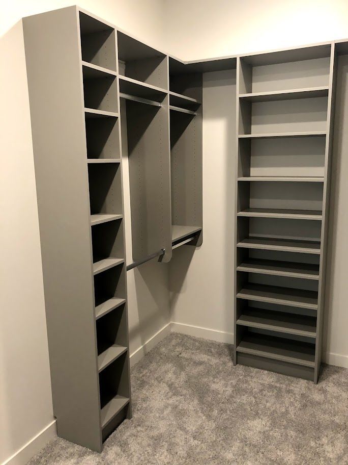 a walk in closet with lots of shelves and a carpeted floor .