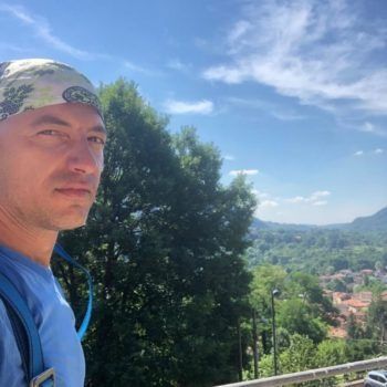 Un uomo che indossa un fazzoletto è in piedi su un balcone che si affaccia su una valle.