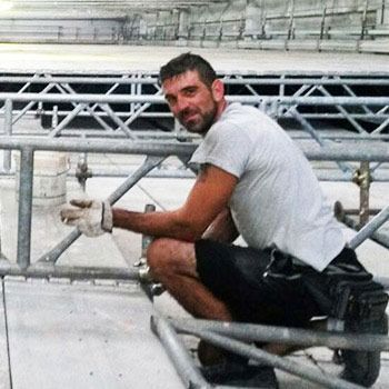 Un uomo è inginocchiato e lavora su una struttura metallica.