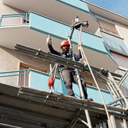 Un uomo è in piedi su un'impalcatura e fa il gesto del pollice in su