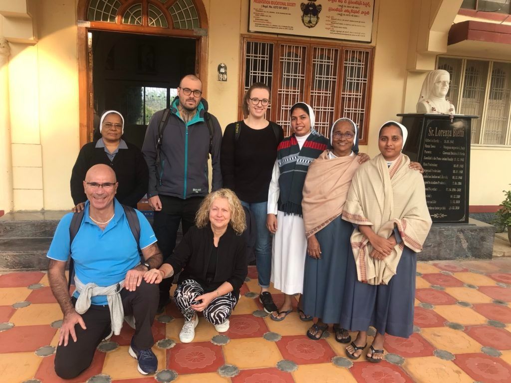 Un gruppo di persone posa per una foto davanti a un edificio.