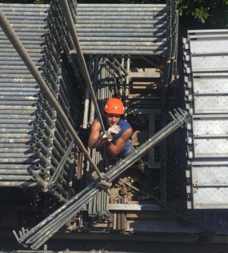 Un uomo che indossa un casco arancione sta lavorando su un'impalcatura
