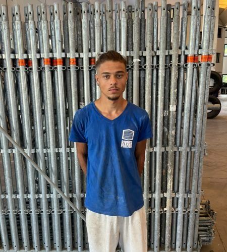 Un uomo con una camicia blu è in piedi davanti a una recinzione. Personale.
