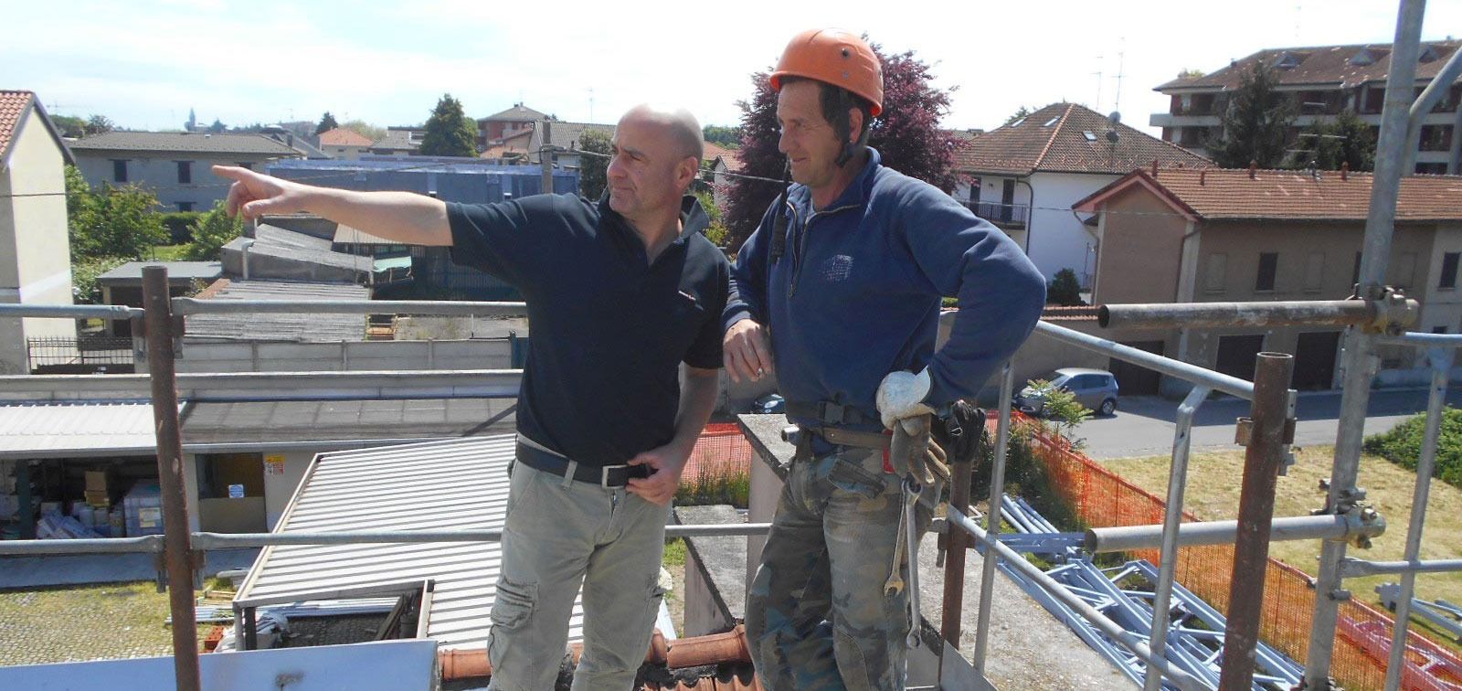 Due operai edili sono in piedi su un'impalcatura in cima a un edificio.