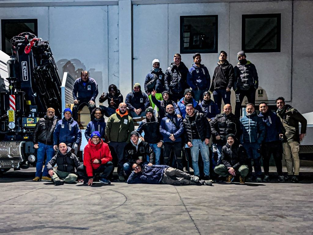 Un gruppo di uomini posa per una foto davanti a una gru