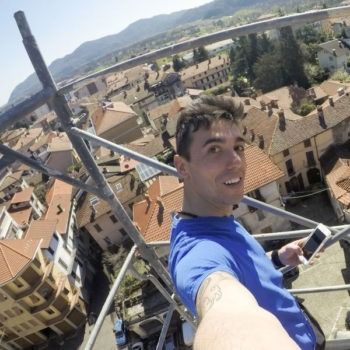 Un uomo con una camicia blu si scatta un selfie in cima a un'impalcatura