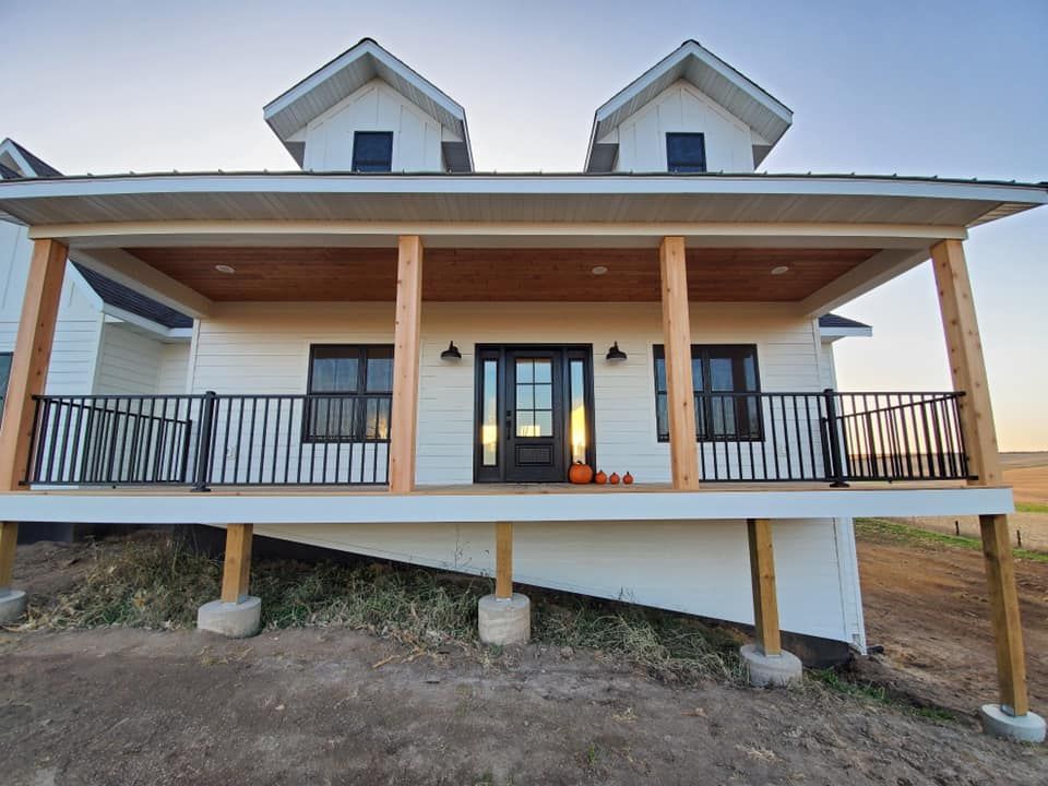 The front of a white house with a large porch.