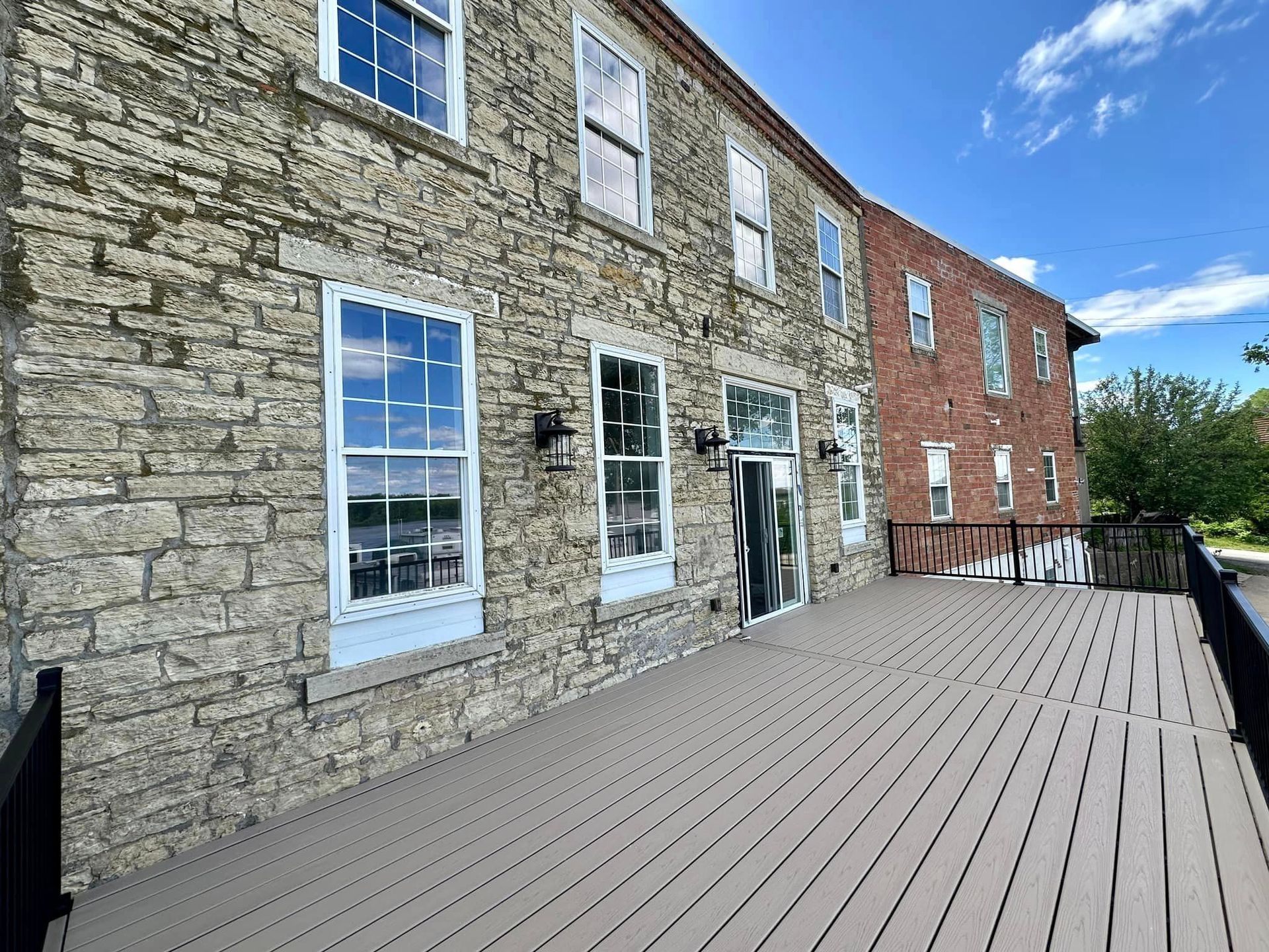 Stone and brick building exterior with a wooden deck; sunny day.