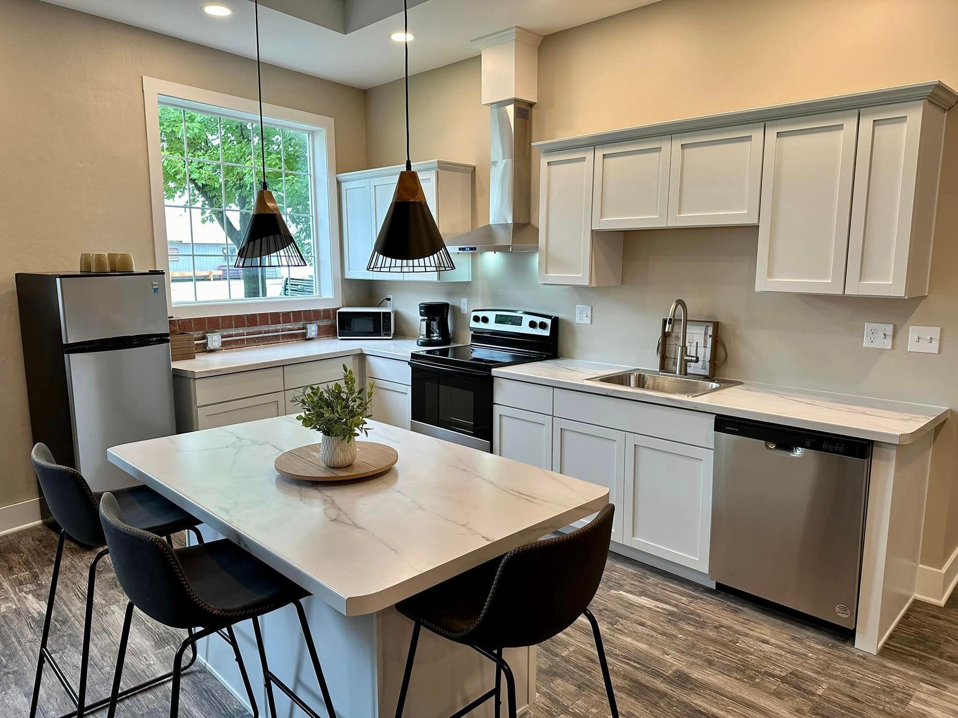 A kitchen with white cabinets , stainless steel appliances , a table and chairs.