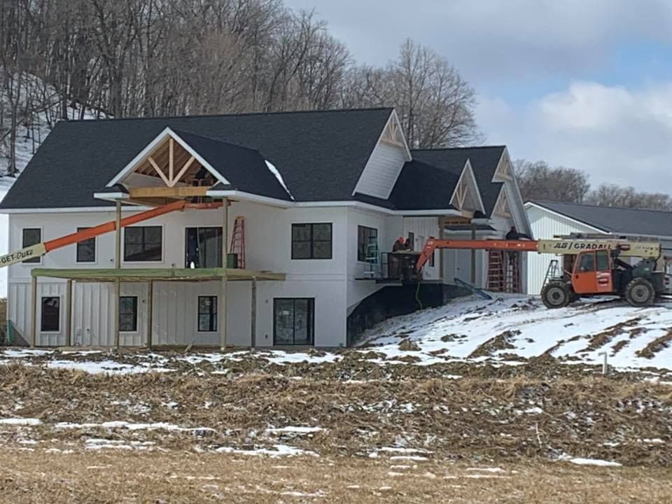 A large white house is being built in a snowy field.