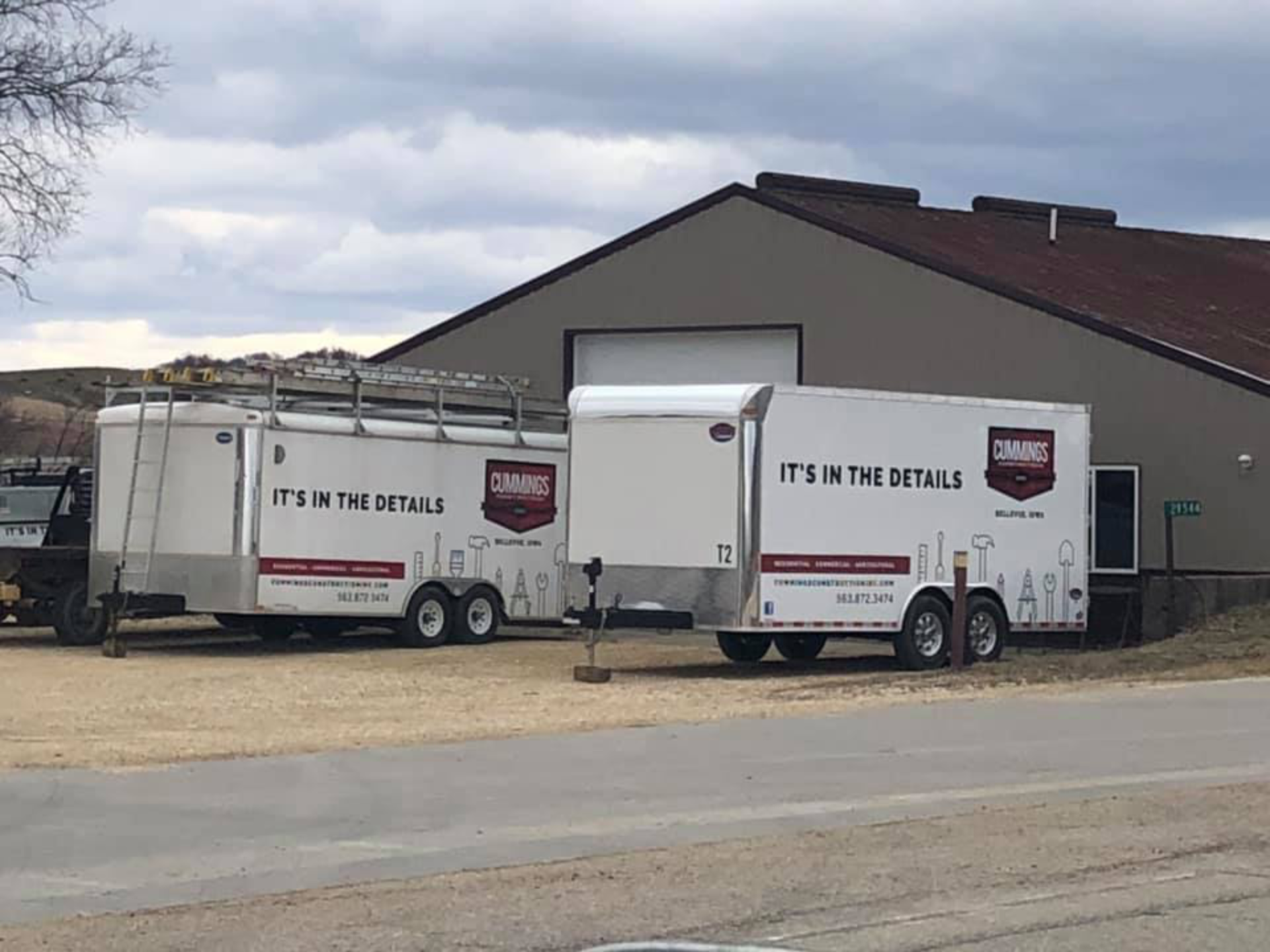 Two white trailers are parked in front of a building.