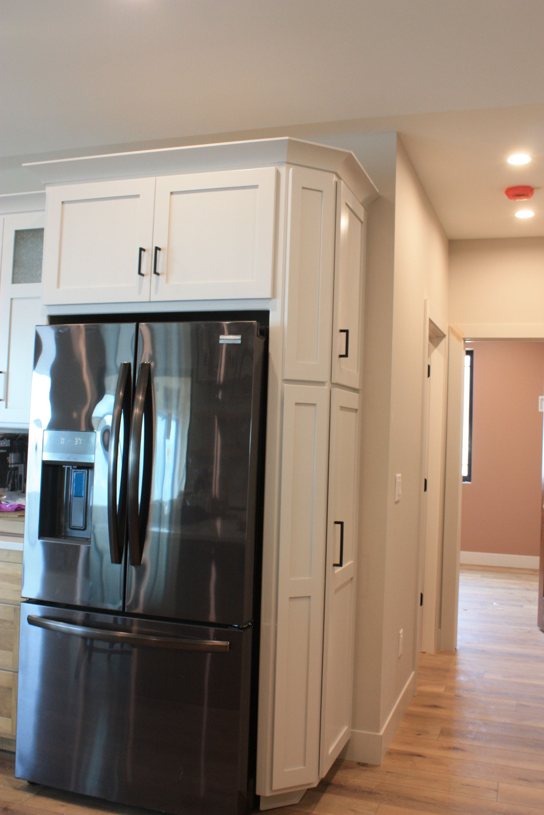 A kitchen with a black refrigerator and white cabinets