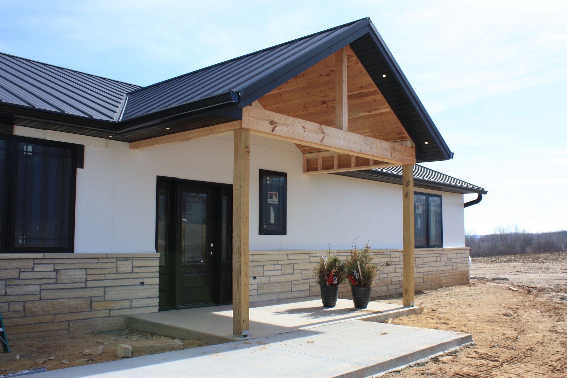 A white house with a black roof and a wooden porch