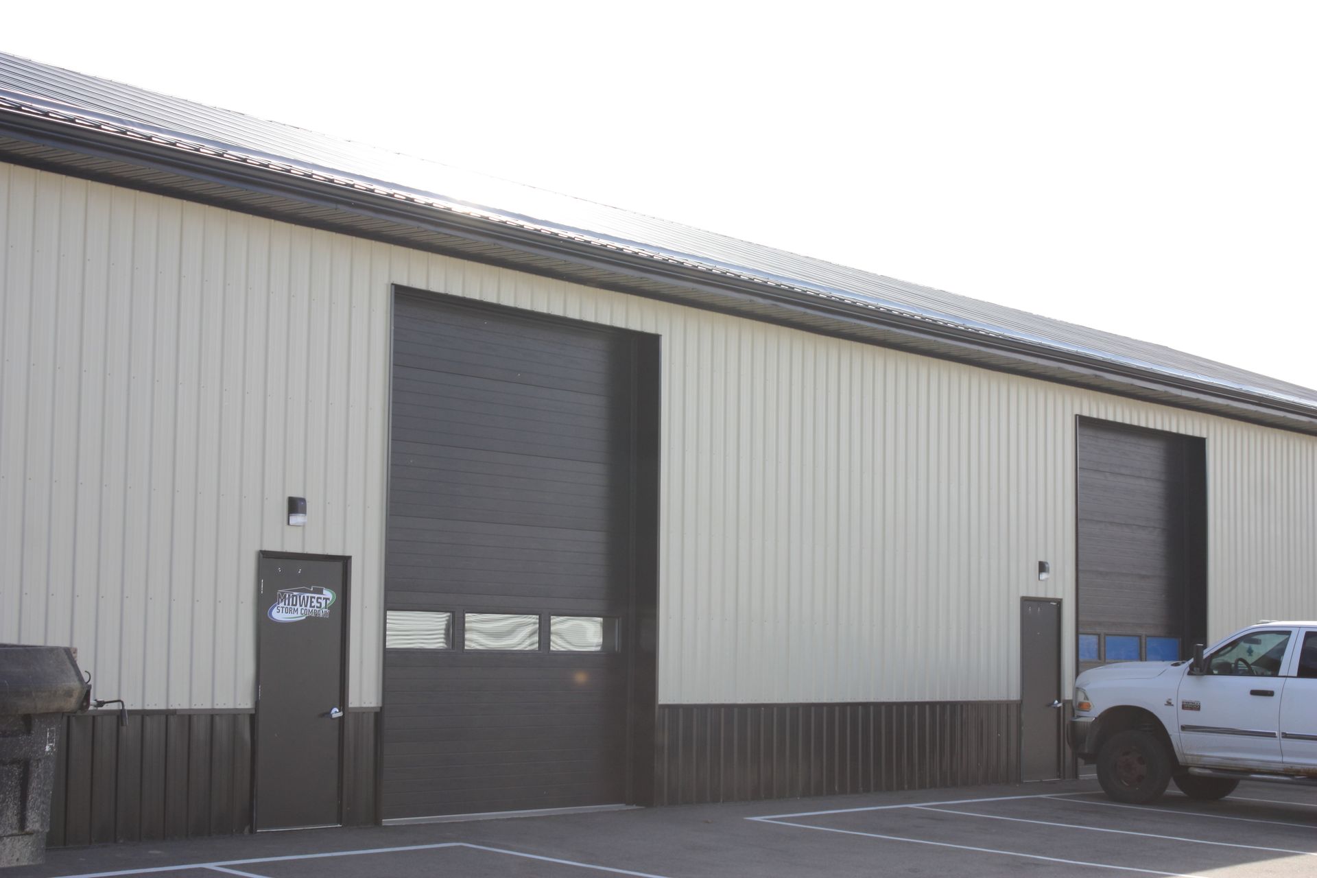Building exterior with two large garage doors, a smaller door, and a parked truck.