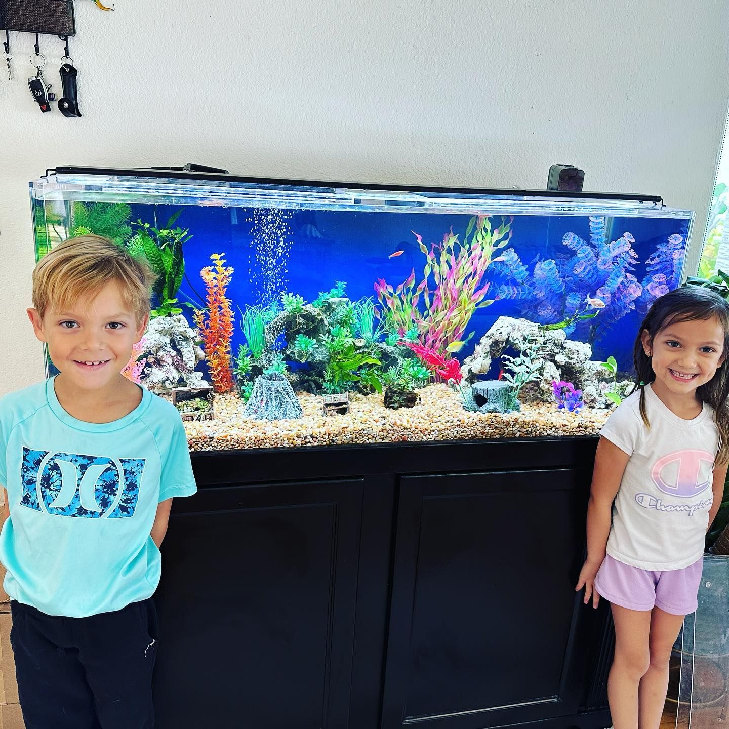 A boy and a girl are standing in front of an aquarium.