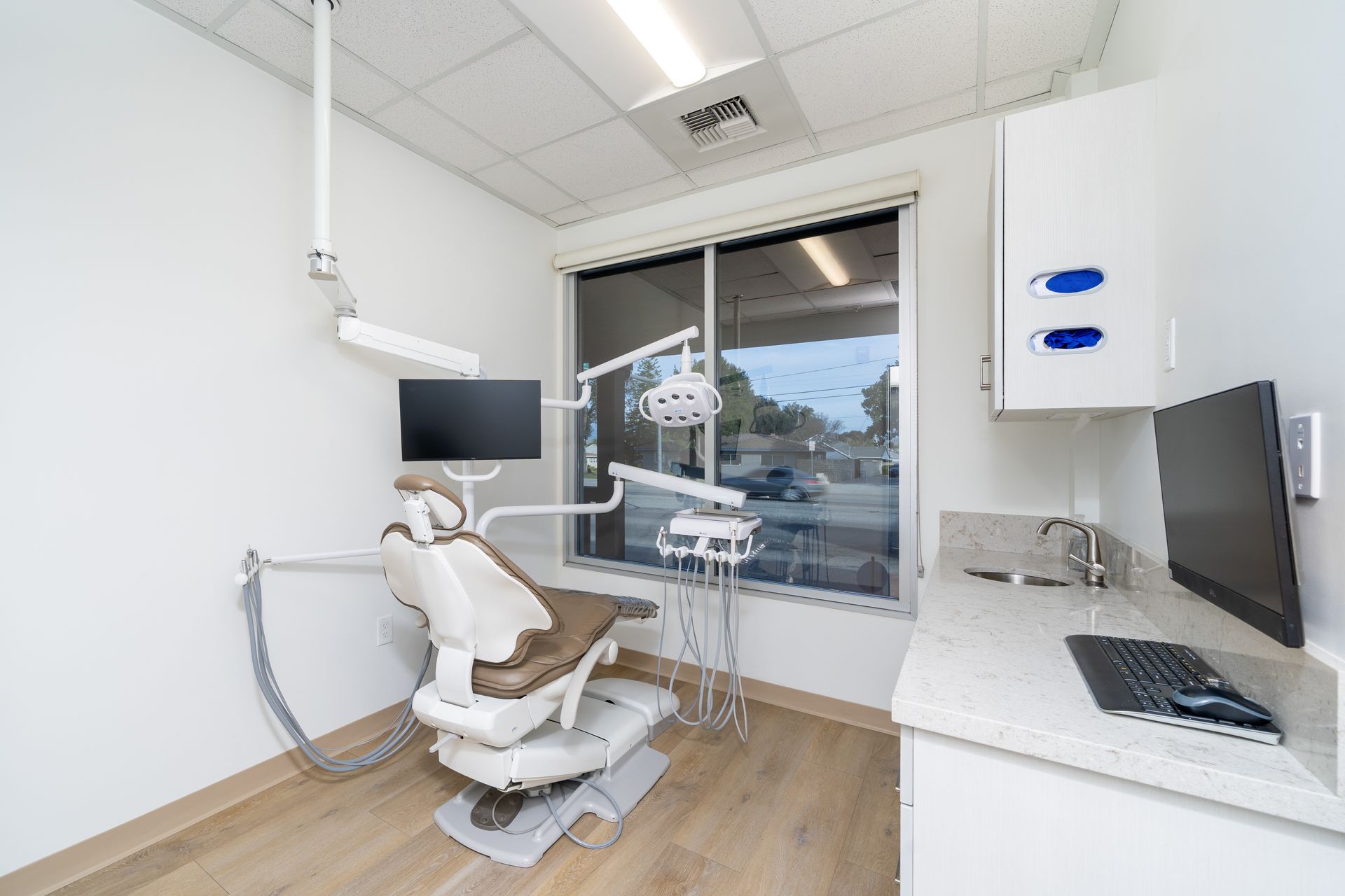 Dental operatory with chair, equipment, computer, and window.