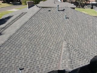 Gray asphalt shingle roof on a residential building, angled view.