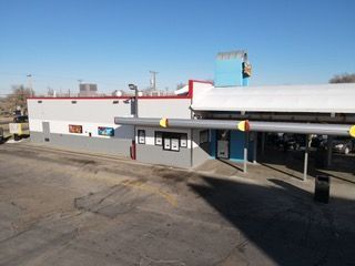 Exterior view of a Sonic Drive-In restaurant on a sunny day. White and blue building with drive-thru stalls.