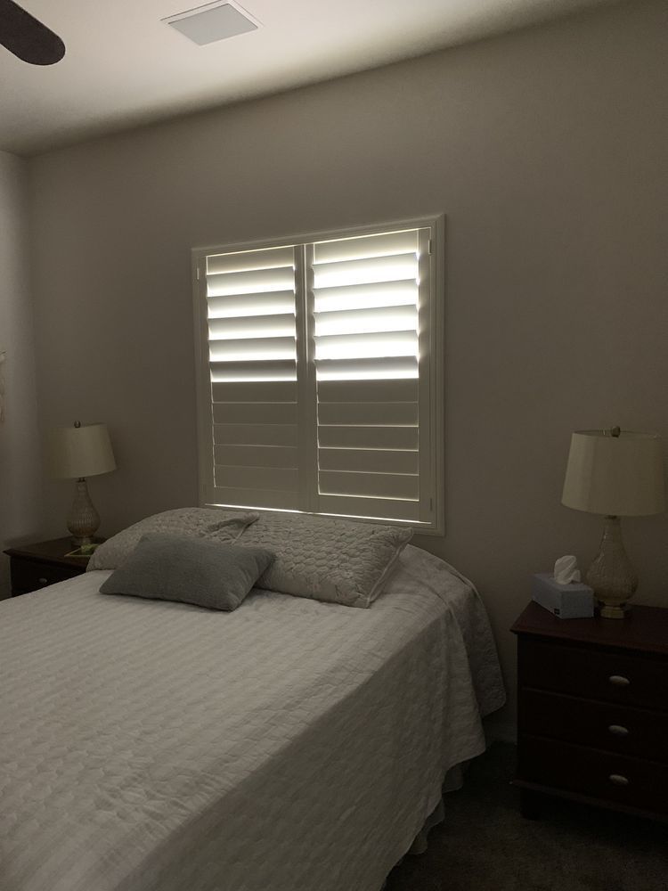 Bedroom with a bed, nightstands, window shutters, and lamps.