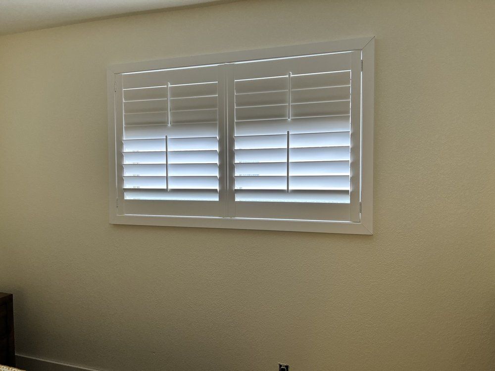 White window shutters on a cream-colored wall.