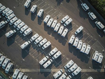 An aerial view of a parking lot filled with lots of white cars