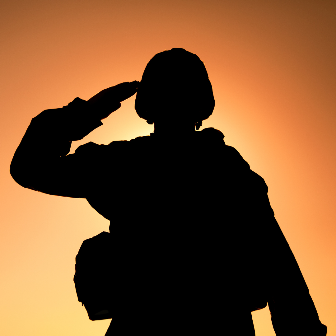 A silhouette of a soldier saluting at sunset