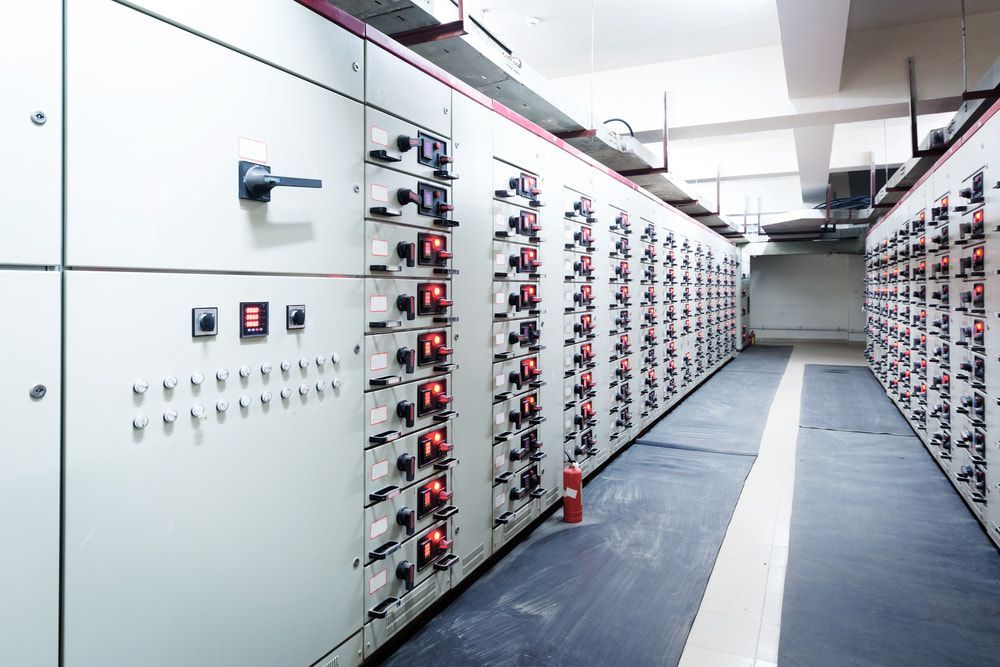 A Row Of Electrical Panels With A Red Fire Extinguisher On The Floor — Max Fox Electrical in Taminda, NSW