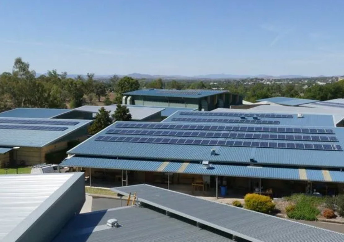 Solar panels on the roof of a large building on a sunny day.