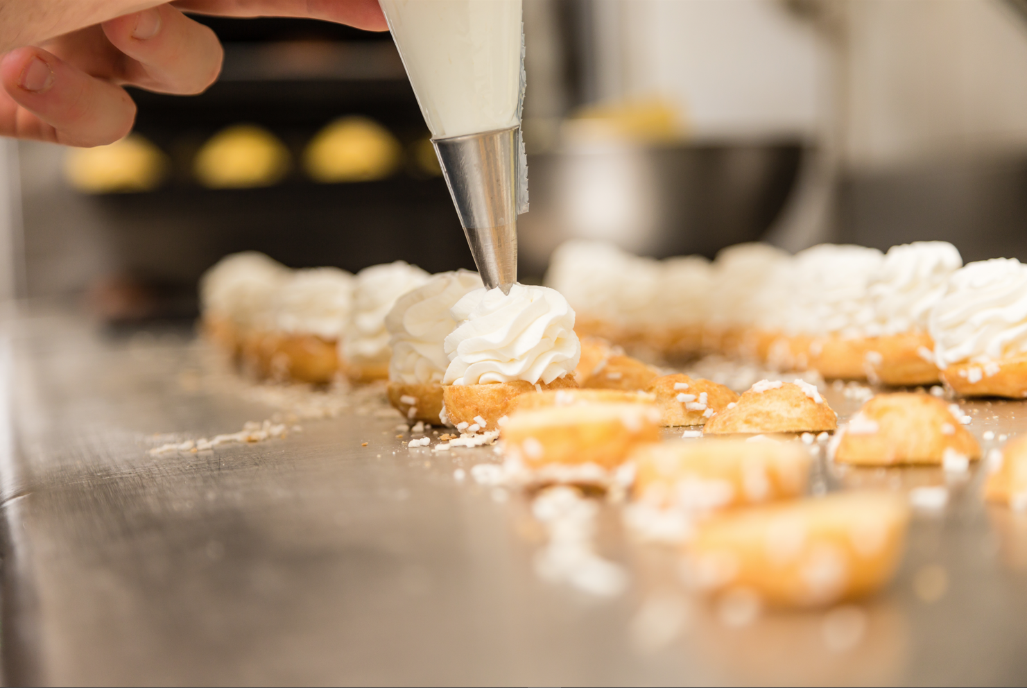 Une personne décore un dessert avec de la crème fouettée.