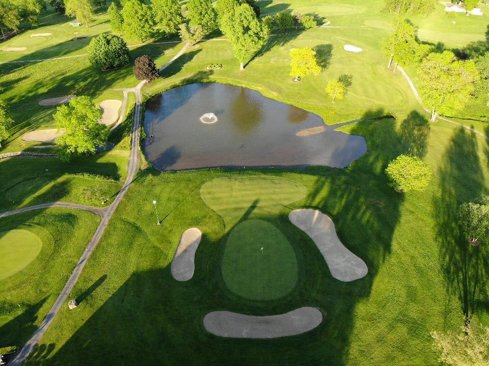 An aerial view of a golf course with a pond in the middle