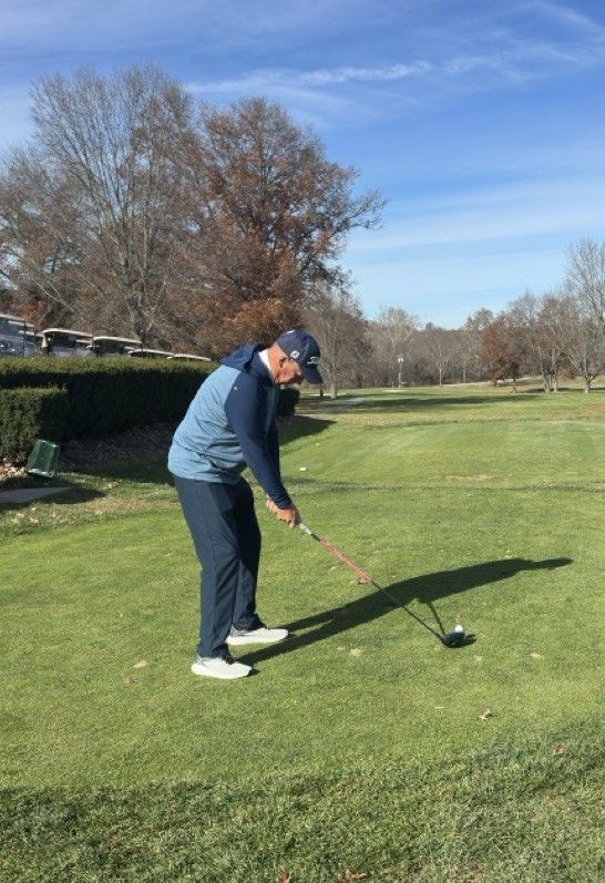 A man is swinging a golf club on a golf course