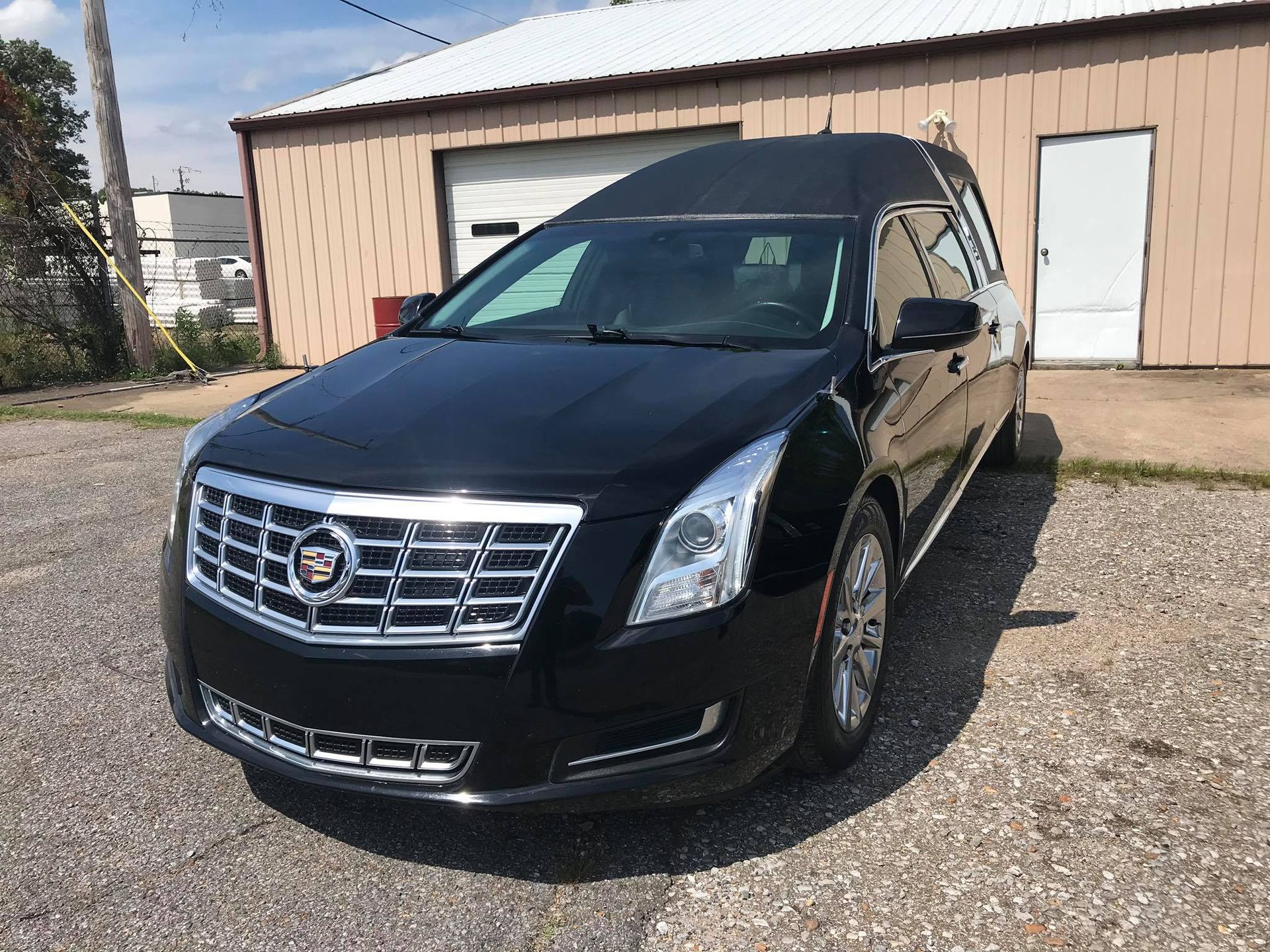 A black cadillac is parked in front of a building.
