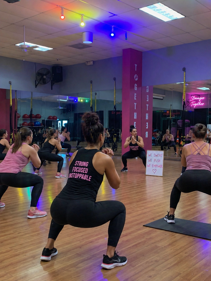 A group of women are posing for a picture in front of a tire in a gym.