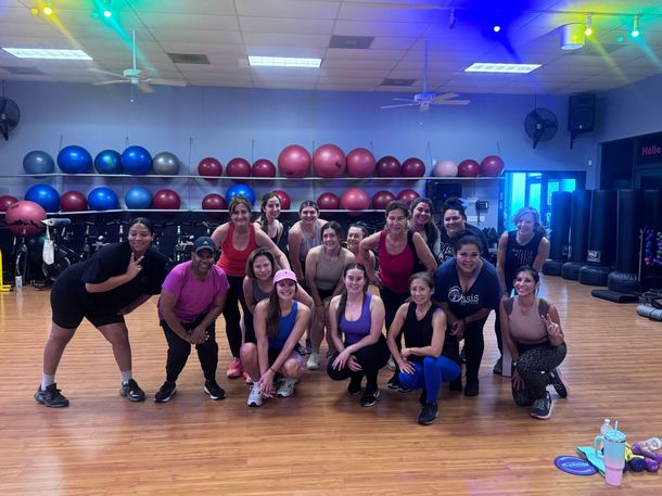 A group of people are sitting on exercise balls in a gym