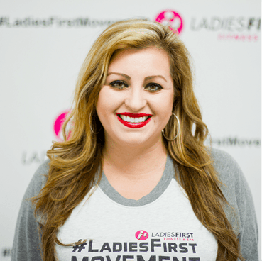 A woman wearing a ladies first movement shirt smiles for the camera