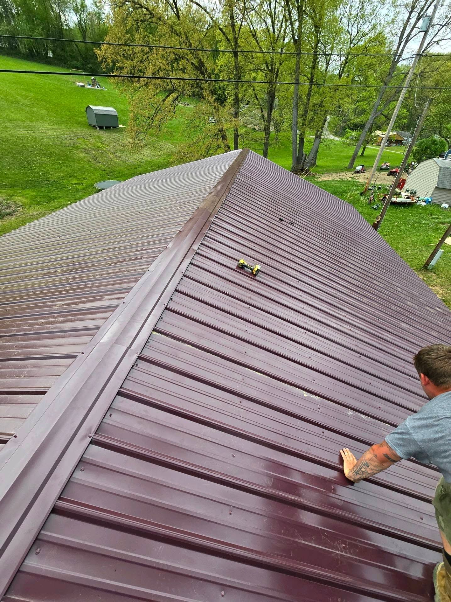 A man is standing on top of a purple metal roof.