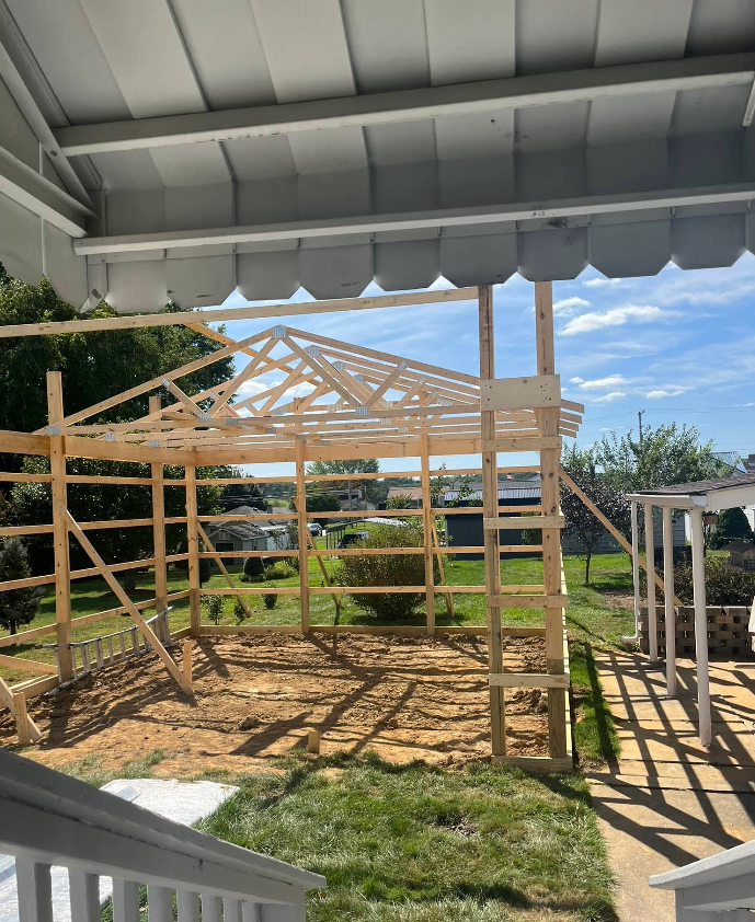 A wooden structure is being built in the backyard of a house.
