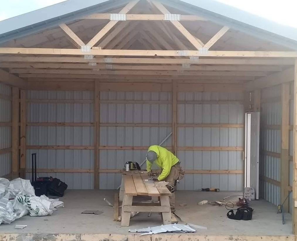 A man is working on a wooden table inside of a building