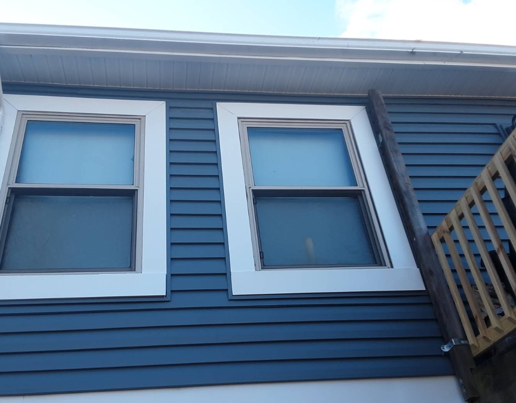 A blue house with two windows and a balcony