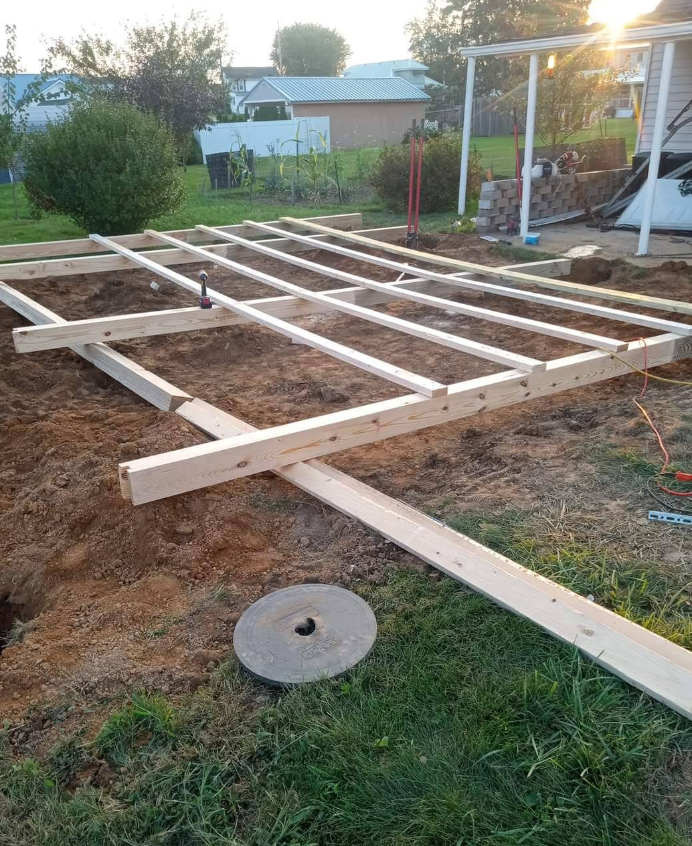 A wooden deck is being built in a backyard.