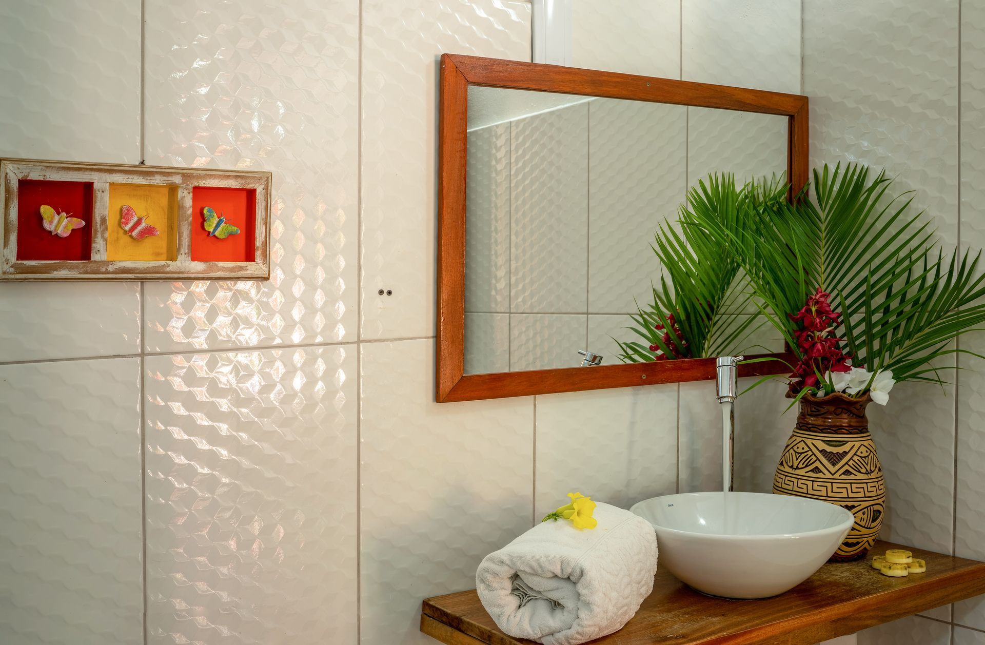 Um banheiro com uma pia, um espelho e um vaso de flores