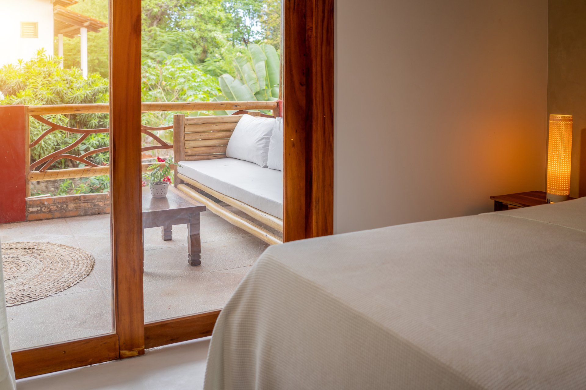 Um quarto com uma cama, sofá, mesa e portas de vidro deslizantes que levam a uma varanda.