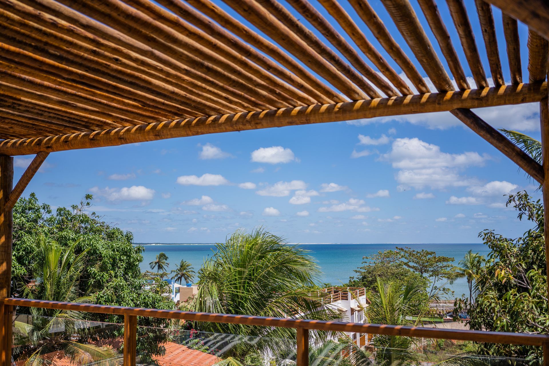 Uma vista do oceano de uma varanda com uma pérgola de madeira.